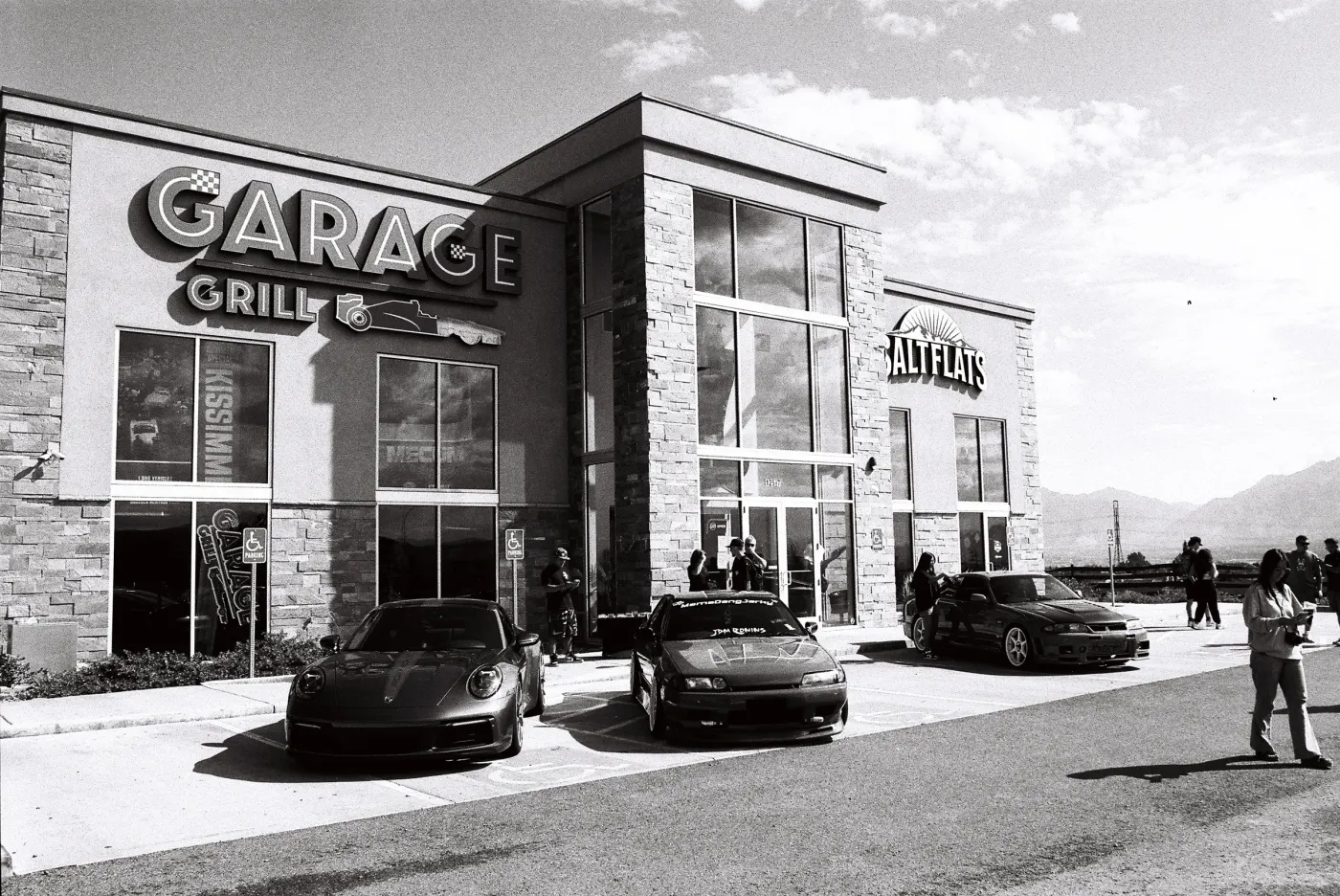 Black and white photo of cars and people gathered outside Garage Grill